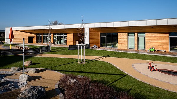 Außenansicht des „World of Kids“ Kindergarten mit Spielplatz.
