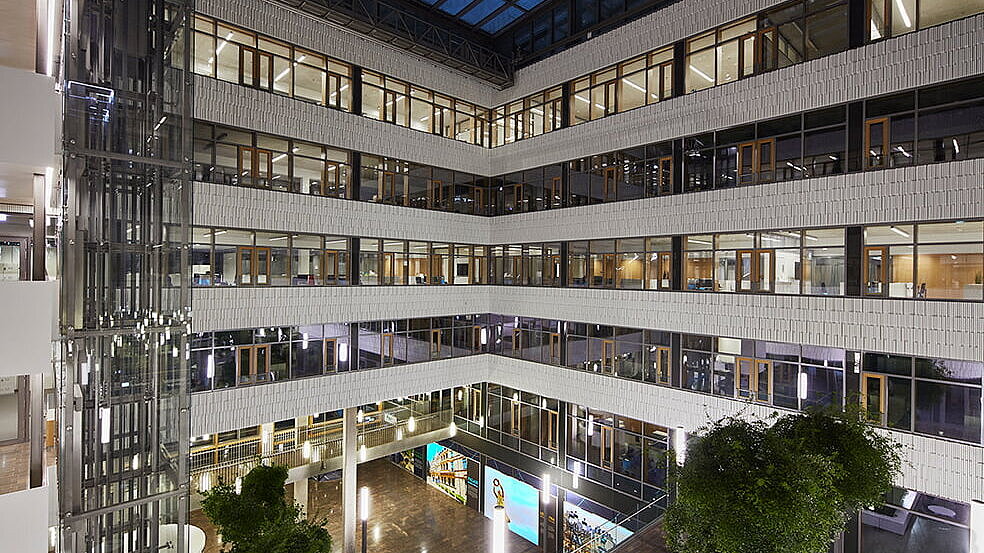 Innenansicht des Postgebäudes in Luxemburg am Abend mit Glasdachkonstruktion LAMILUX PR60 Passivhaus und modernem Atrium.