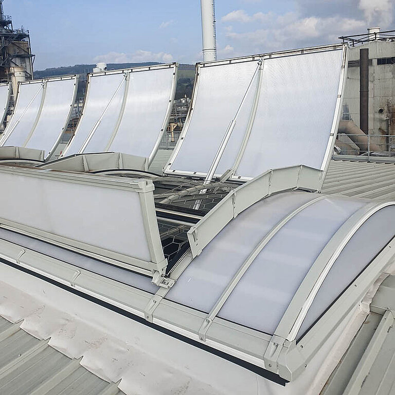 Mehrere geöffnete LAMILUX Lichtband B RWA auf Industrie-Flachdach mit bogenförmiger Verglasung