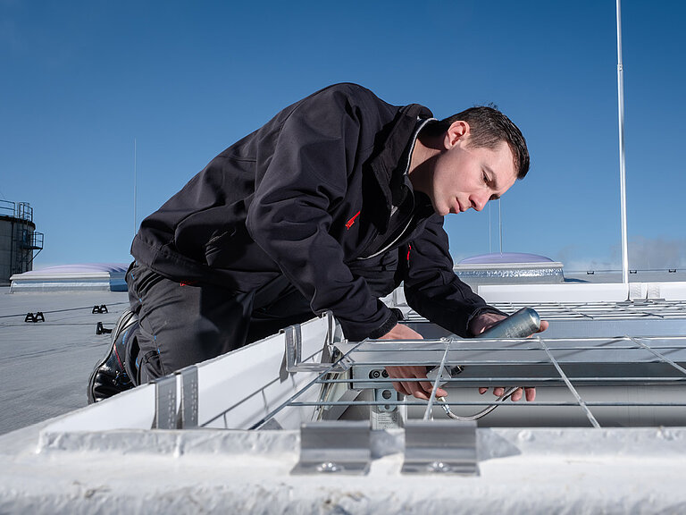 Handwerker montiert ein Tageslichtelement auf einem Flachdach