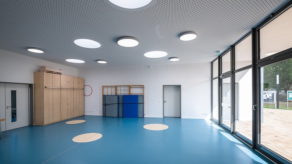 Turnhalle der Kita Sonnenfeld mit runden Oberlichtern an der Decke und großen Fenstern.