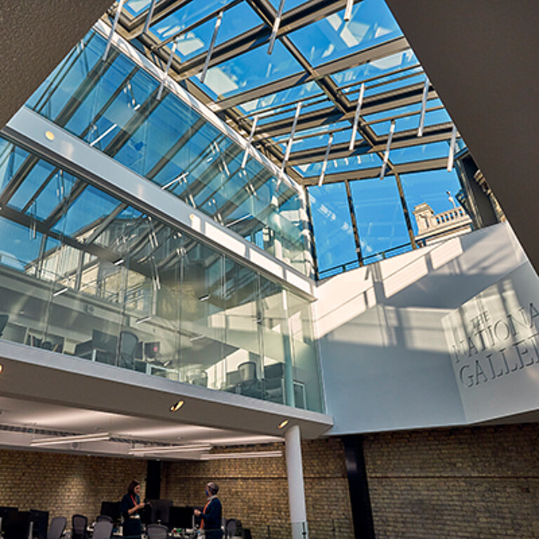 Modernes Glasdach über einem mehrgeschossigen Atrium mit transparenter Stahl-Glas-Konstruktion, das großzügig Tageslicht in den Innenraum eines öffentlichen Gebäudes leitet