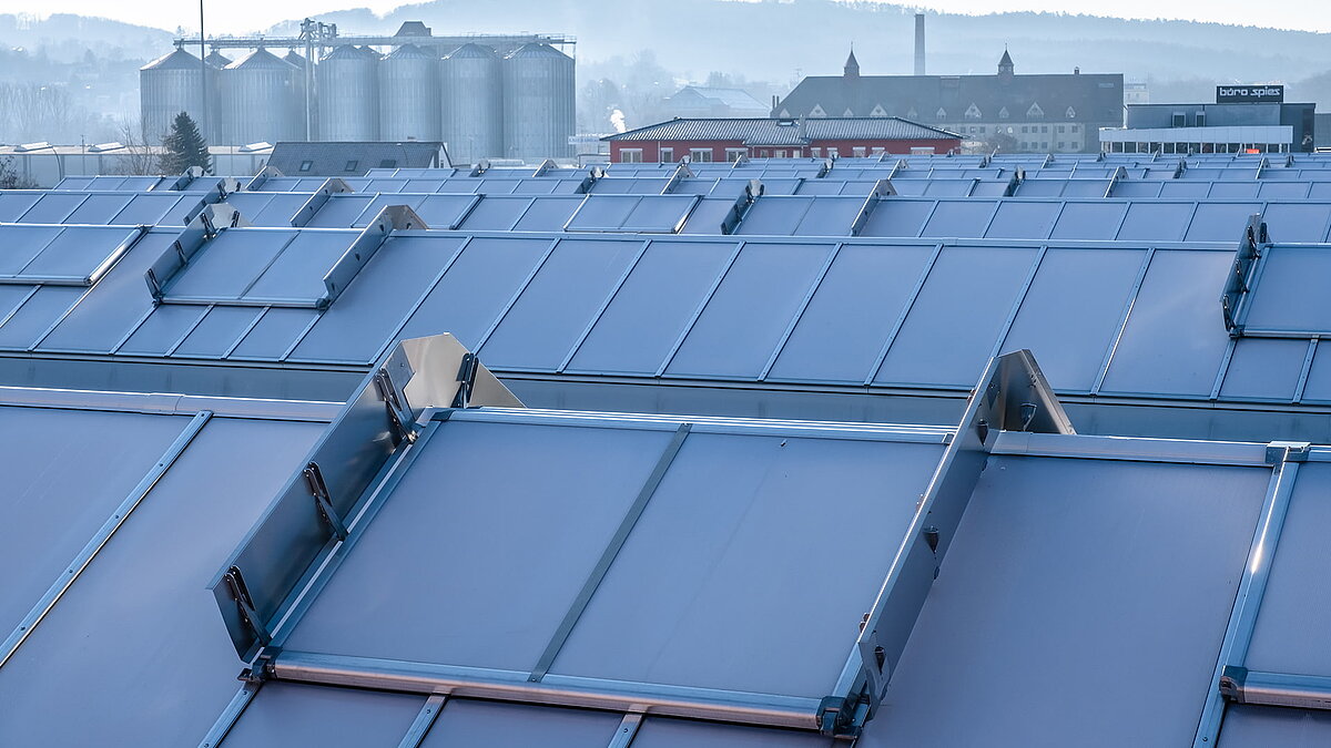 Dach des OBI Baumarkts in Bamberg mit modernen Lichtbändern zur natürlichen Belichtung, im Hintergrund Silos und Industriegebäude.