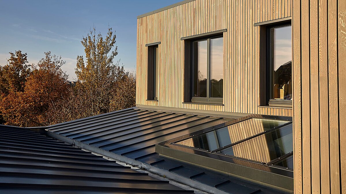 Modernes Gebäude der Potton Show Homes in England mit LAMILUX Glasdach PR60 und Holzfassade im warmen Abendlicht.