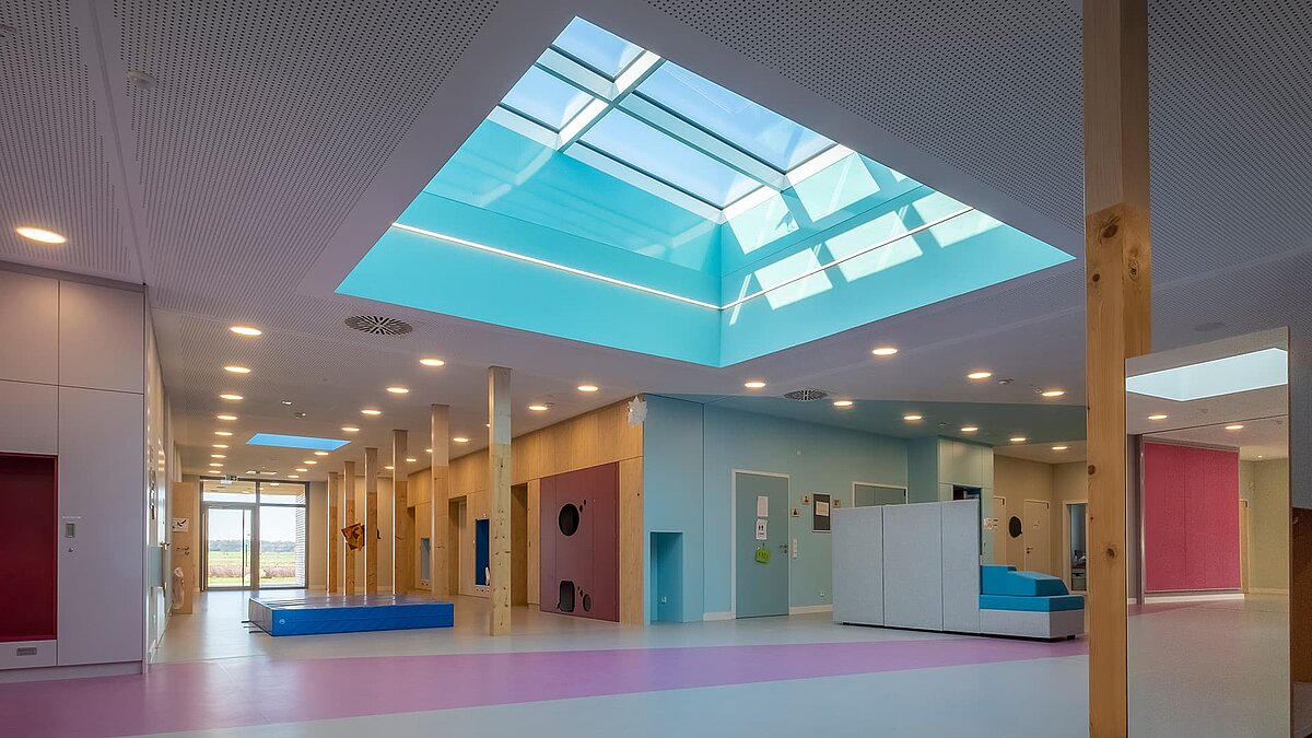 Innenansicht des Kindergartens „World of Kids“ mit LAMILUX Flachdachfenster FE 3° und Glasdach PR60, die eine helle und freundliche Atmosphäre schaffen.