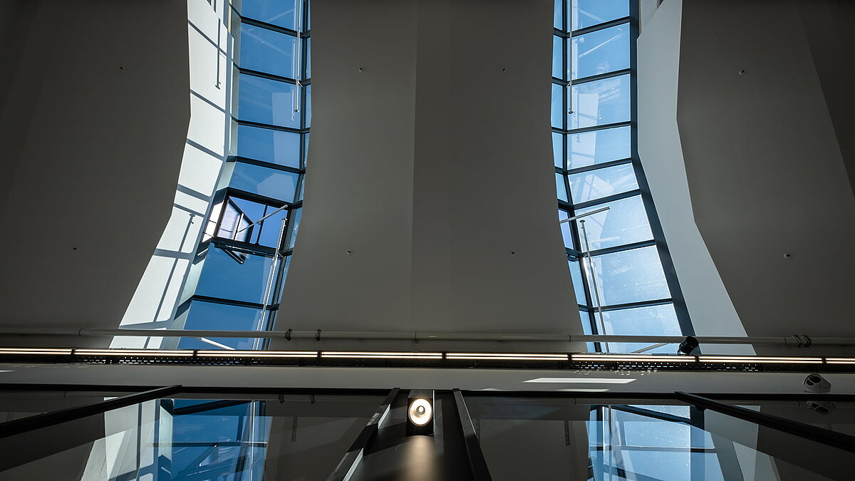 Modernes Glasdach PR60 des Outlet Centers Selb mit geschwungenen Wänden und geöffnetem Fensterelement.