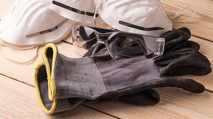 Handschuhe, Schutzbrille und Atemschutz als Sicherheitskleidung für Dachdecker bei der Flachdachabdichtung mit Flüssigkunststoff
