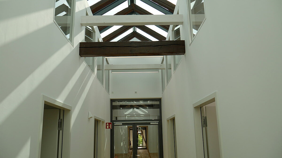 Lichtdurchfluteter Gang der Leibniz-Universität Hannover mit Glasdach und sichtbaren Holzbalken.