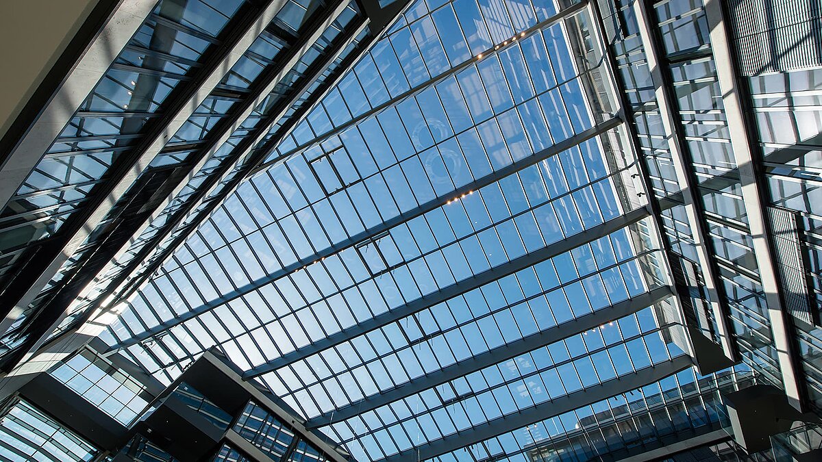 Modernes Glasdach im FGS Campus, das den Himmel reflektiert und das lichtdurchflutete Atrium umgibt.