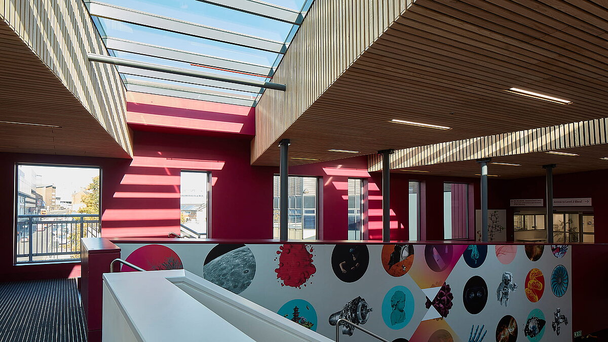 Innenbereich der Sheffield Hallam University mit LAMILUX Glasdach PR60, modernem Holzelementen und bunter Wandgestaltung.