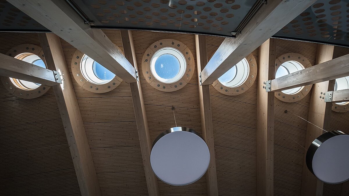 Innenansicht des Hafenterminals Norderney mit runden Flachdach Fenstern und Holzdecke.