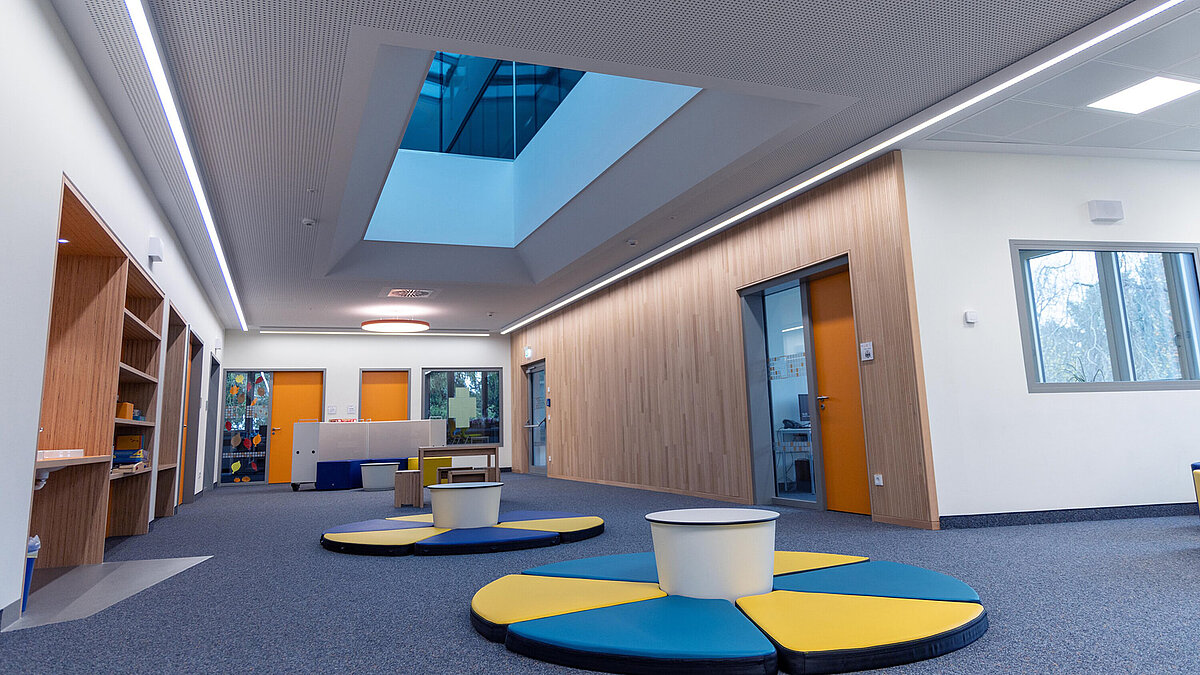 Flur im Schulzentrum Burgebrach mit LAMILUX Glasdach PR60 und farbenfroher Einrichtung.