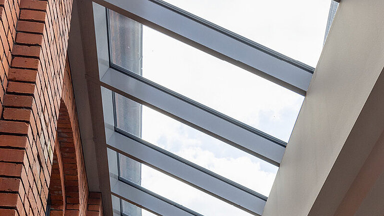 LAMILUX Brandschutzfenster als durchlaufendes Oberlicht mit feuerwiderstandsfähiger Verglasung in Flur- oder Atriumbereich zwischen Ziegelwand und Innenraum