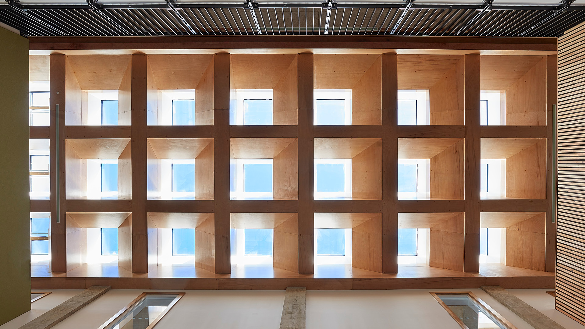 Innenansicht eines Raums mit rasterförmig angeordneten quadratischen Dachoberlichtern in Holzdecke und gleichmäßigem Tageslichteinfall