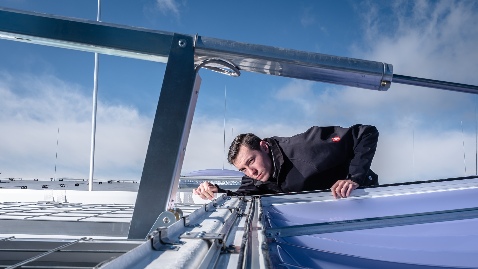 Handwerker montiert ein Tageslichtelement auf einem Flachdach unter Glasstruktur